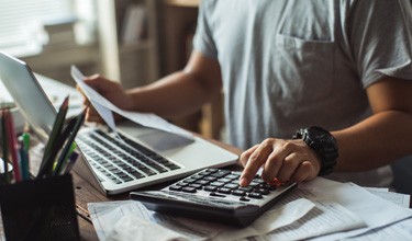 man using calculator and laptop