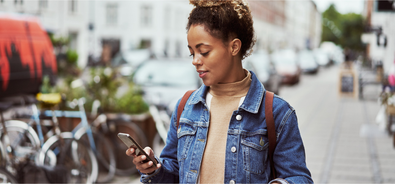 Woman walking down city street while looking at her smart phone