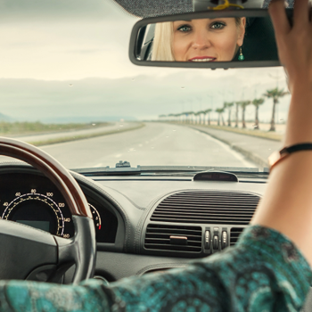 Woman driving a car and looking in rearview mirror