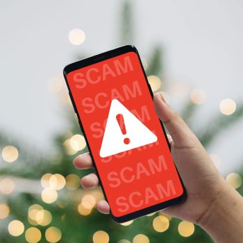 A smartphone showing a warning sign indicating a scam alert