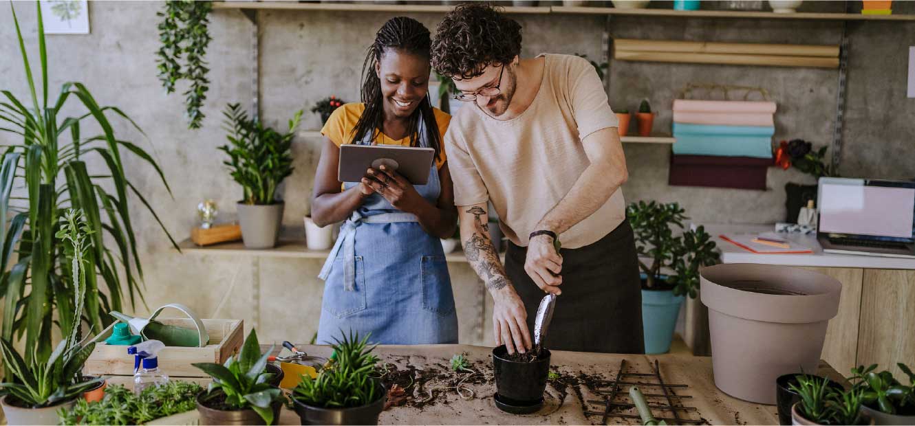 Man and woman working in garden shop to pot plants.