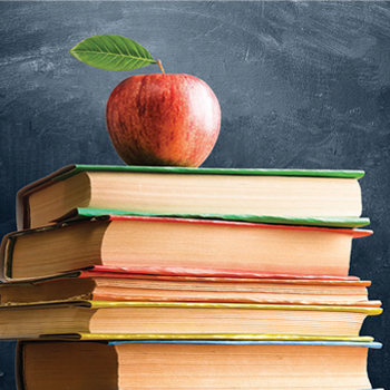 Apple on top of a stack of books with a chalkboard background.