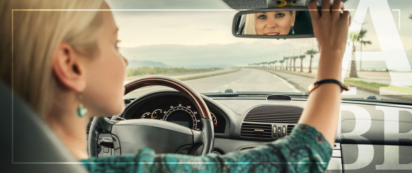 Lady looking in auto rearview mirror while driving