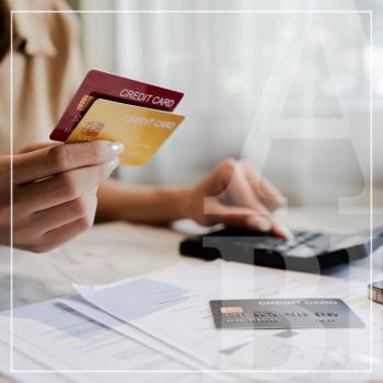 A woman holding credit cards is comparing while using a calculator