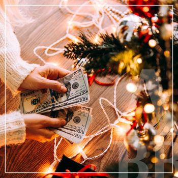 Hands counting cash while leaning over the holiday decorations