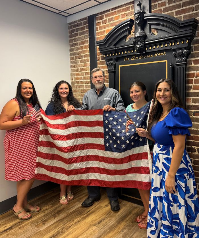 CBC employees dress in red, white, and blue while holding an American flag to celebrate America's 250th birthday