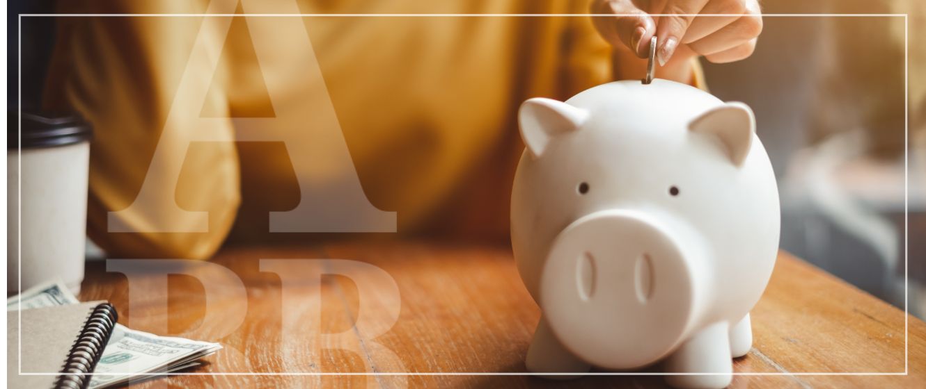 A woman putting a coin into a piggy bank