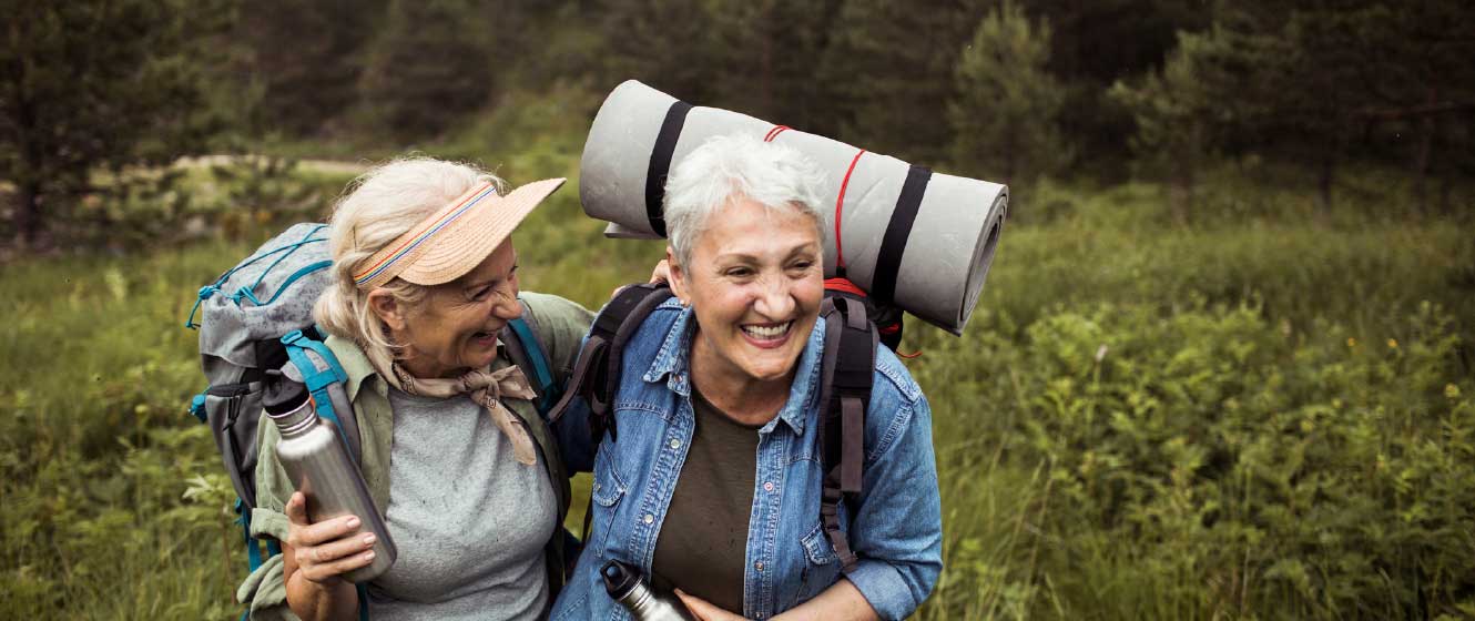 Two mature women hiking together and smiling