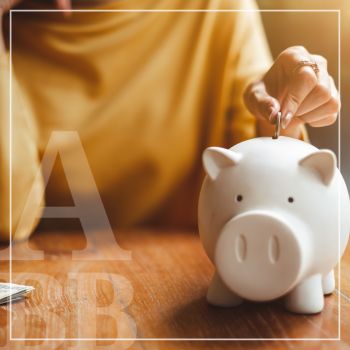 A woman putting a coin into a piggy bank